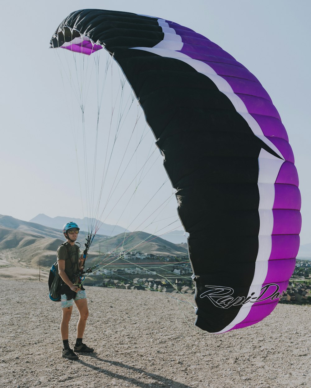man in blue shirt and black shorts with white and purple parachute in the sky