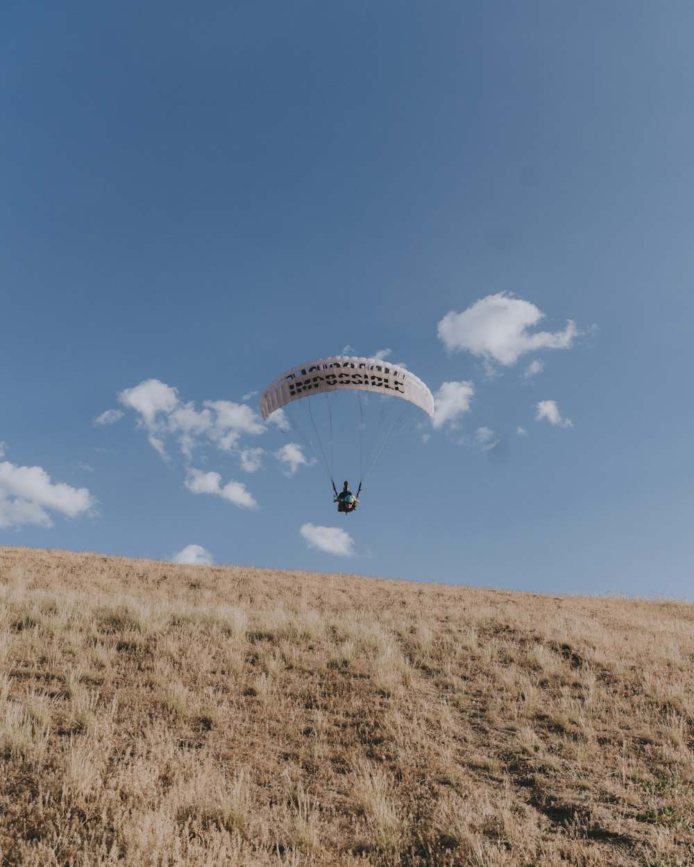 person in blue shirt with yellow parachute in the sky