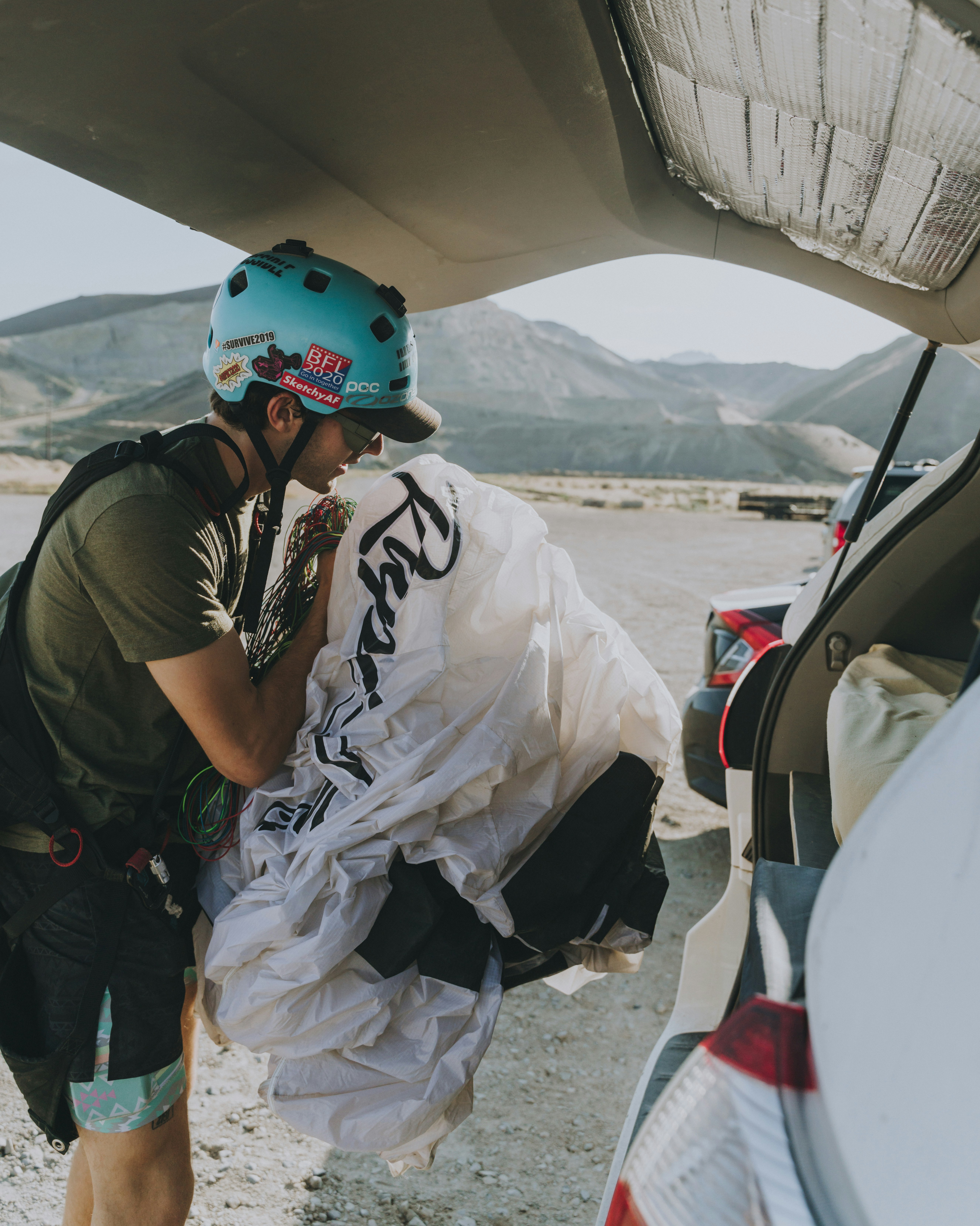 man in black t-shirt and white pants standing beside white car during daytime