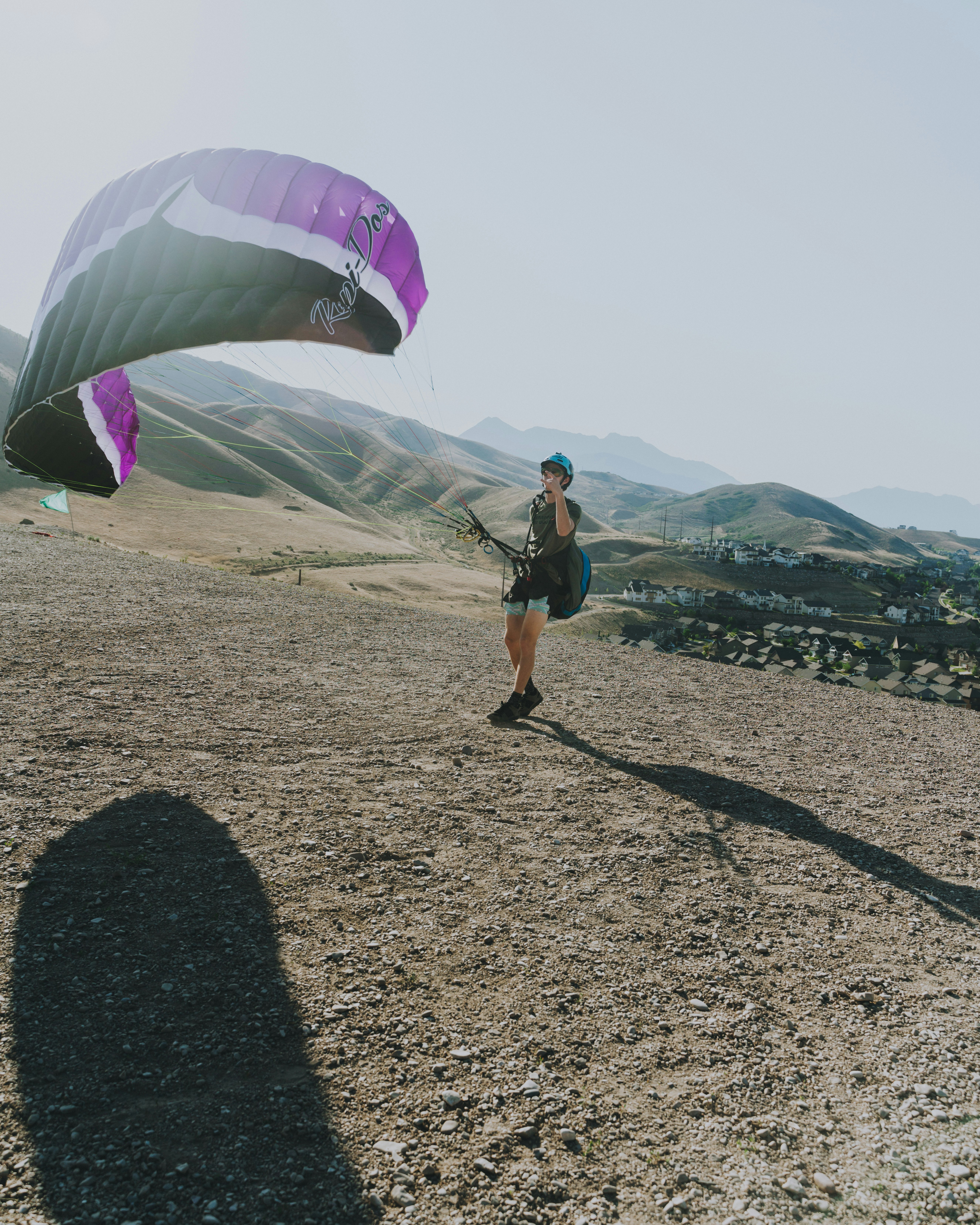 man in black t-shirt and black shorts holding purple and white parachute
