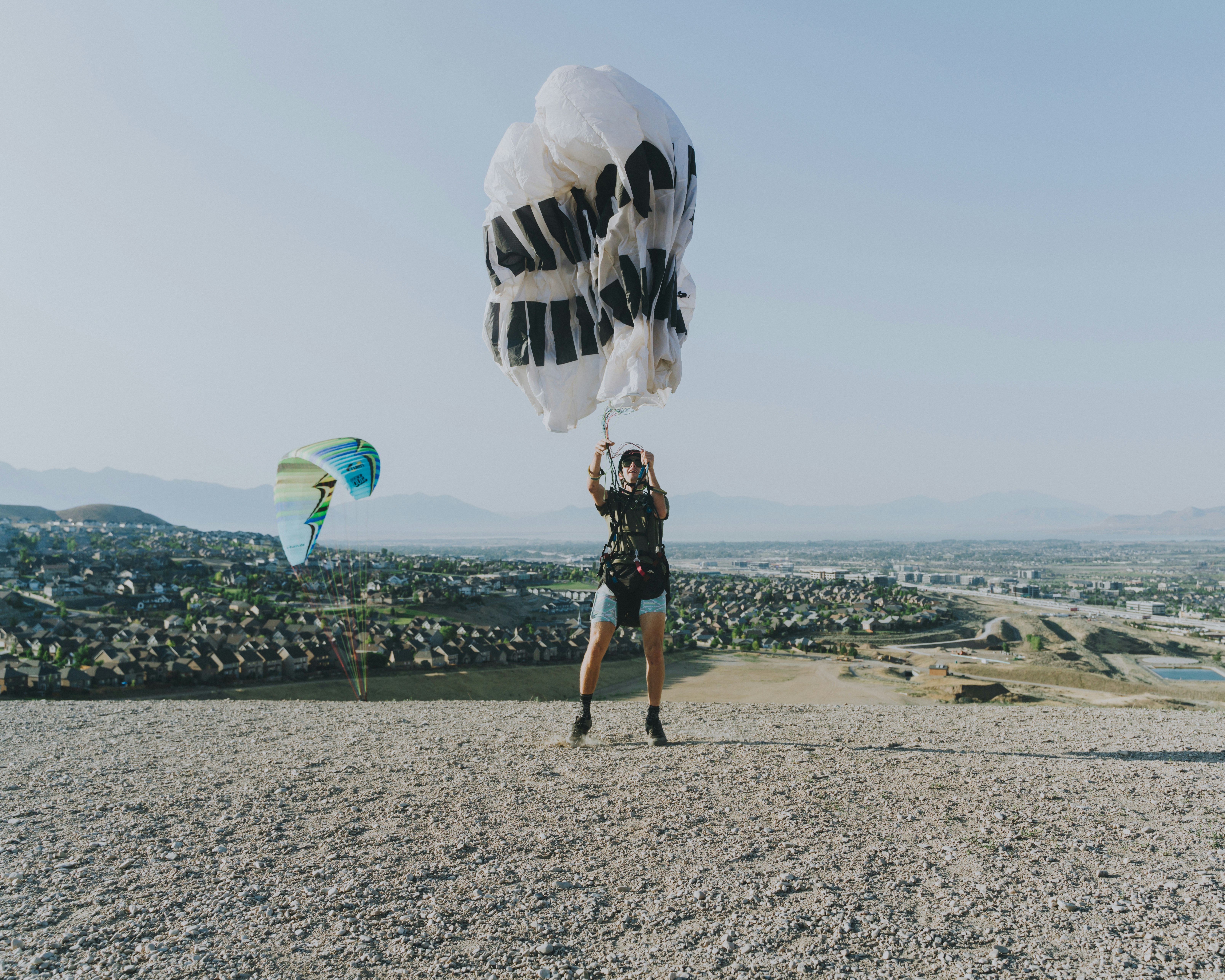man in black shorts and black shirt carrying blue and white parachute