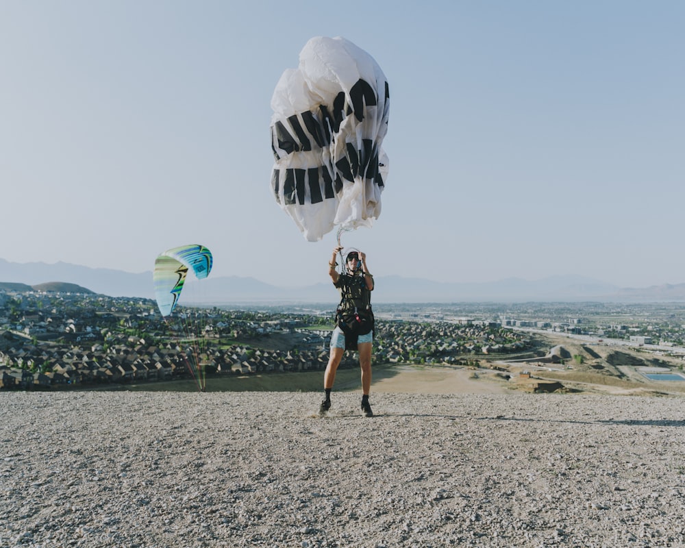 man in black shorts and black shirt carrying blue and white parachute