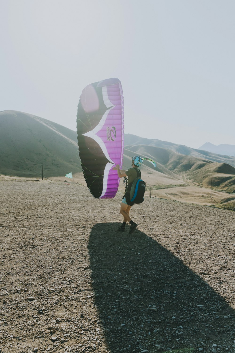 man in green shirt and black shorts holding white and pink surfboard