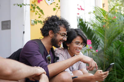 Smiling couple using a mobile app for travel safety alerts in a vibrant urban plaza.
