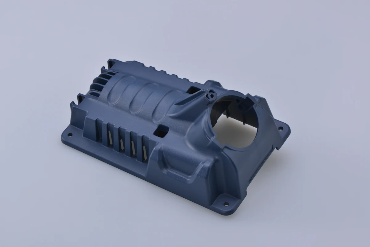 A blue-gray molded manifold with integrated ports and mounting bosses