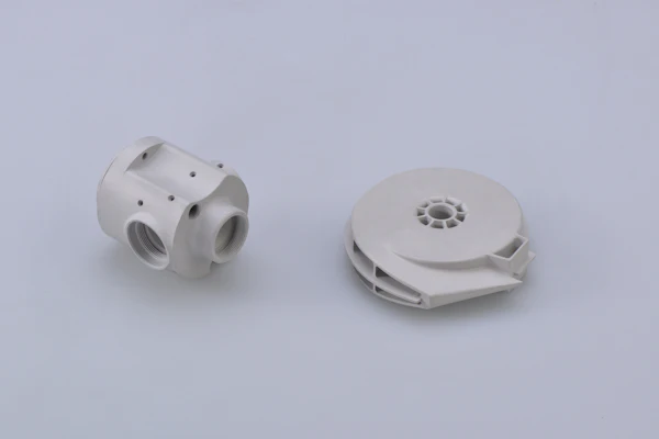 Two white molded housings, a ported valve body and a ribbed impeller cover