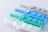 A collection of silicone button pads in pastel colors including blue, teal, and gray. Each pad has visible labeled buttons such as 'Mute', 'Mix', and 'Sel'. The buttons have a soft, rubbery texture and are arranged in a neat row.