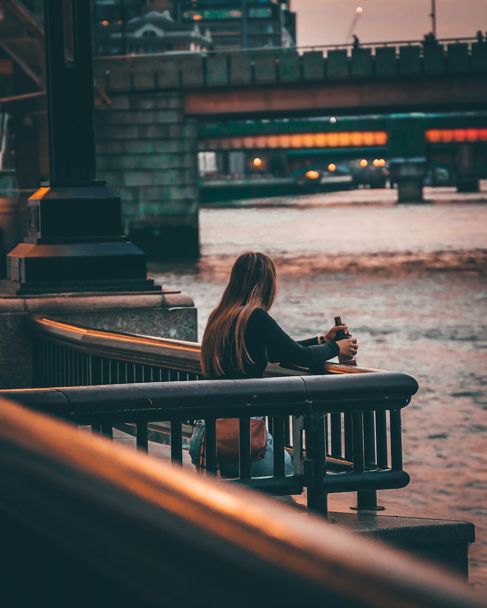 woman in black long sleeve shirt sitting on brown wooden bench during daytime