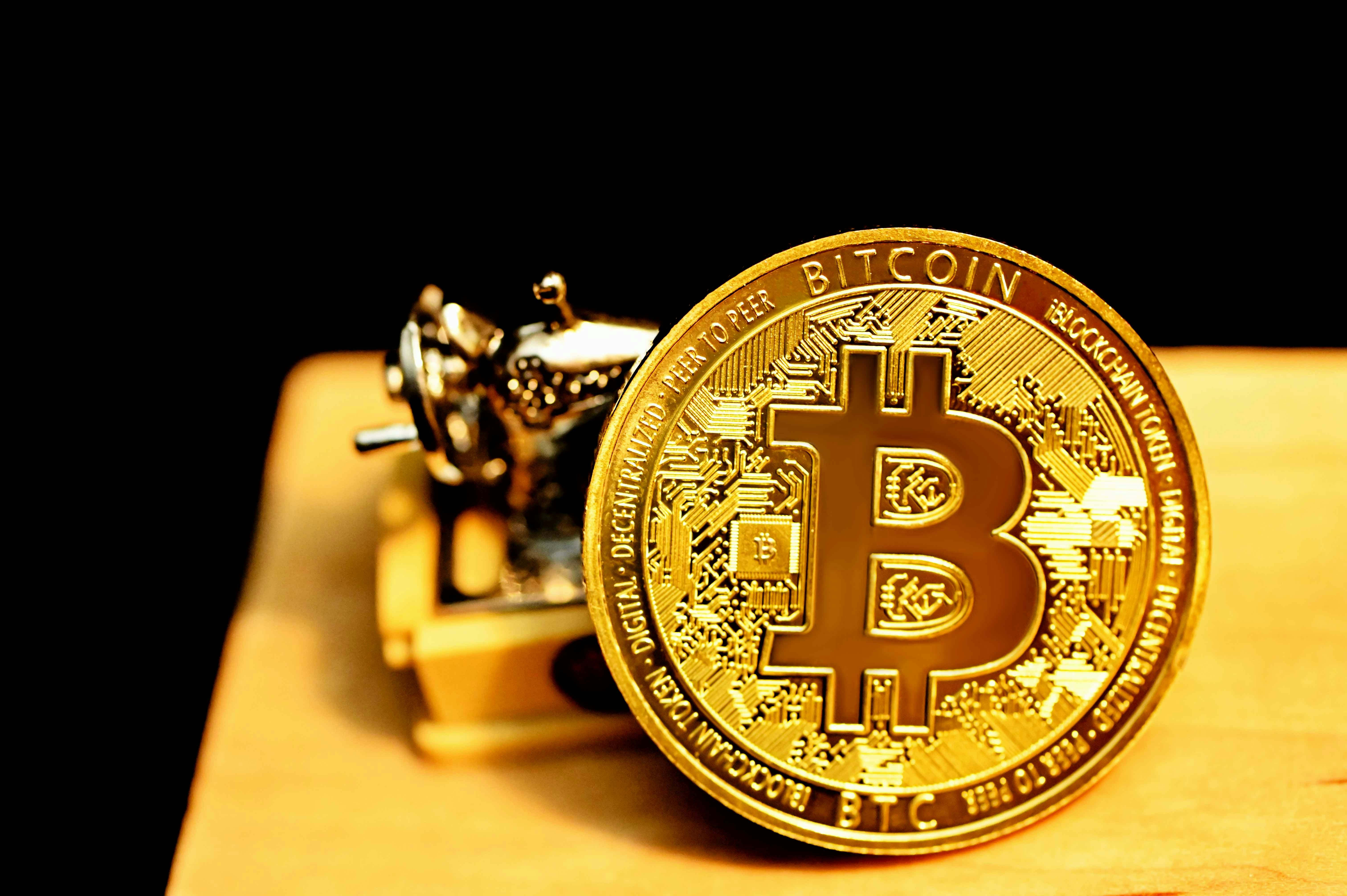 A bitcoin propped up against a miniature sewing machine on a table.