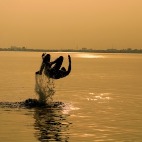 silhouette of man surfing on sea during sunset