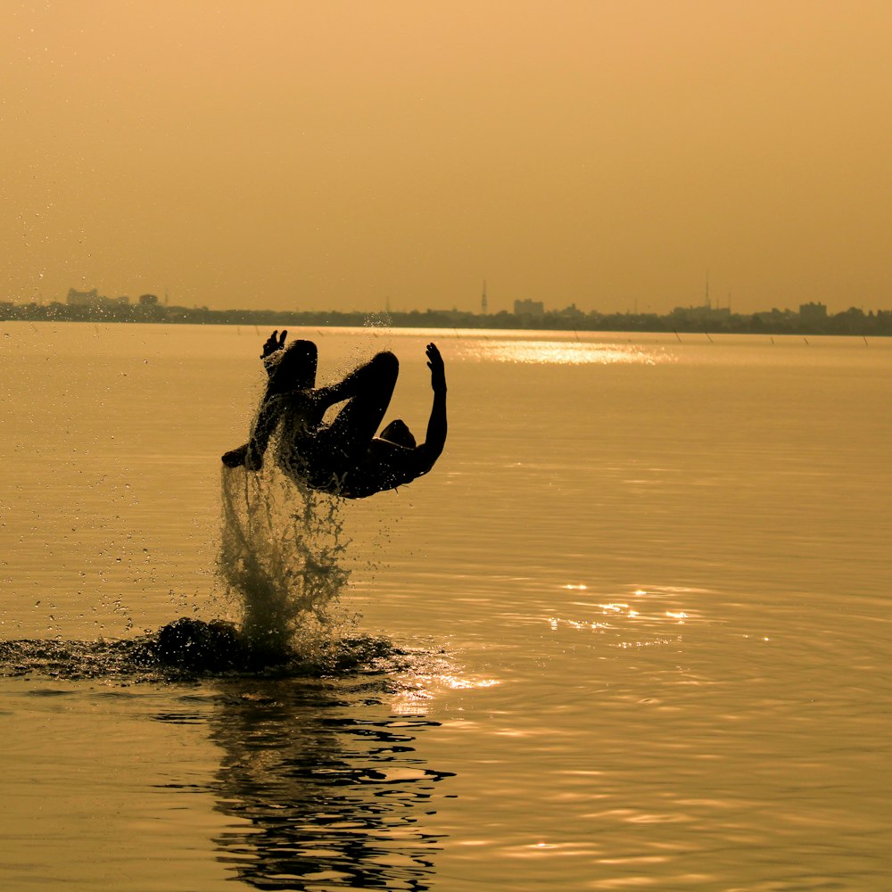 silhouette of man surfing on sea during sunset