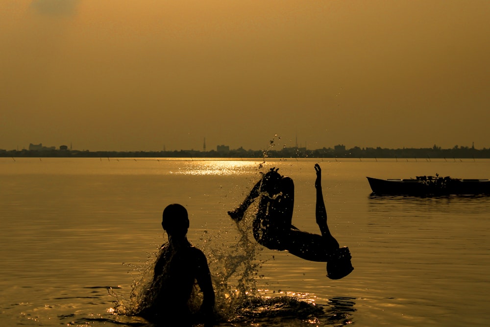 silhouette of man and woman on water during sunset