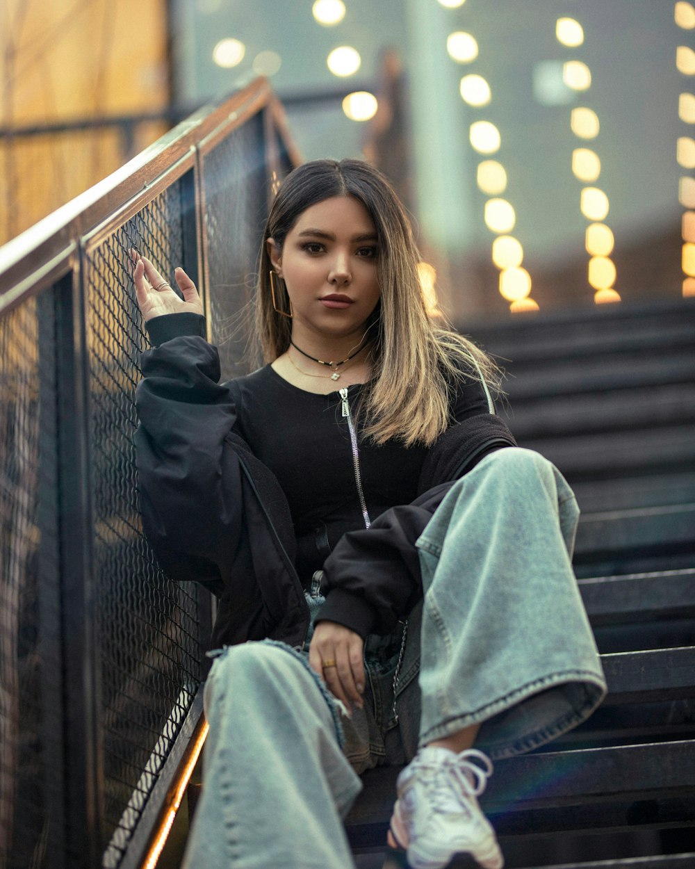 woman in black long sleeve shirt and blue denim jeans sitting on black wooden bench during