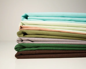Stacks of neatly folded premium sustainable textiles showcasing rich textures and neutral tones