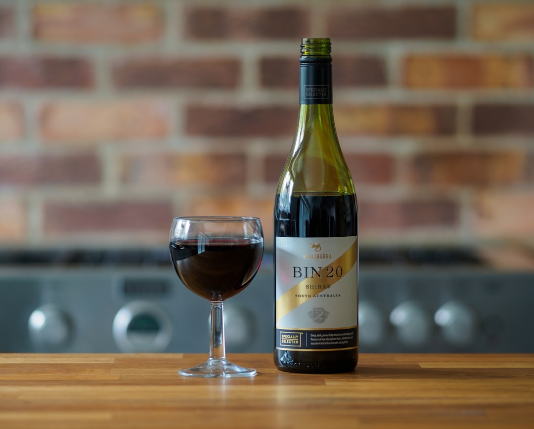 wine bottle beside wine glass on brown wooden table