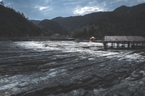Compact emergency shelter pitched beside a flowing stream under a cloudy sky.