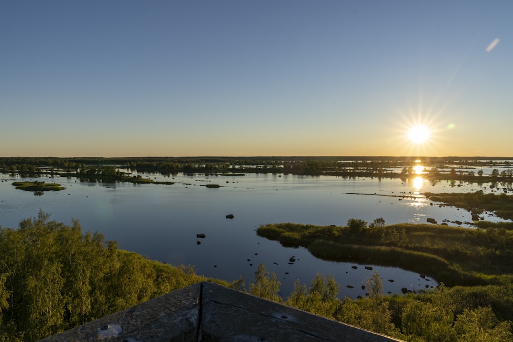 body of water near green grass during sunset