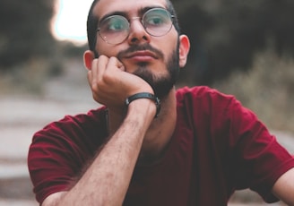 man in red crew neck t-shirt wearing black framed eyeglasses