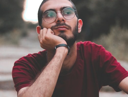 man in red crew neck t-shirt wearing black framed eyeglasses