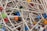 A tangled collection of metallic sewing pins with colorful, round plastic heads in various shades like black, red, blue, yellow, and green.
