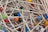 A tangled collection of metallic sewing pins with colorful, round plastic heads in various shades like black, red, blue, yellow, and green.