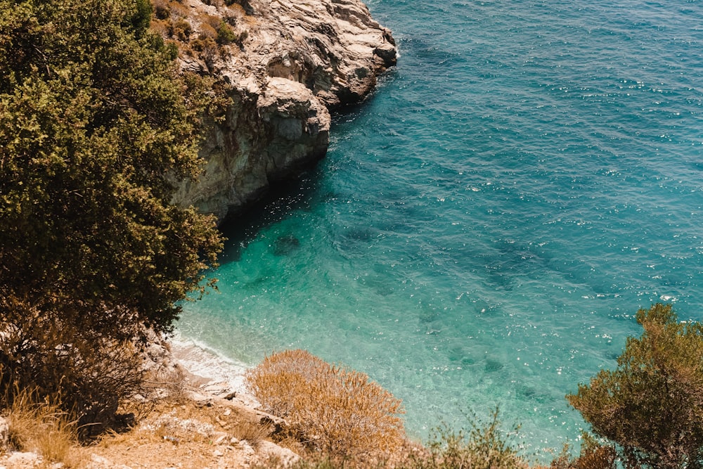 green and brown rocky mountain beside blue sea during daytime