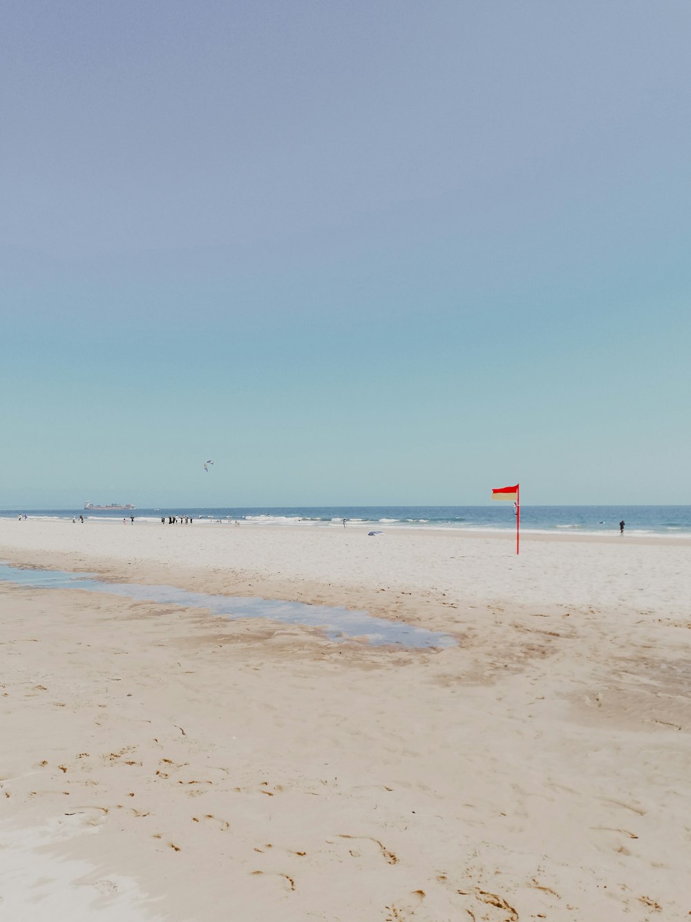 red and white flag on beach during daytime