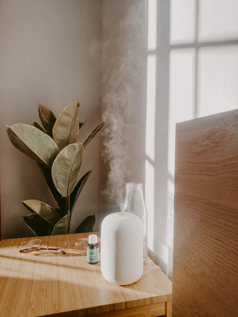 White diffuser releasing steam on a wooden desk