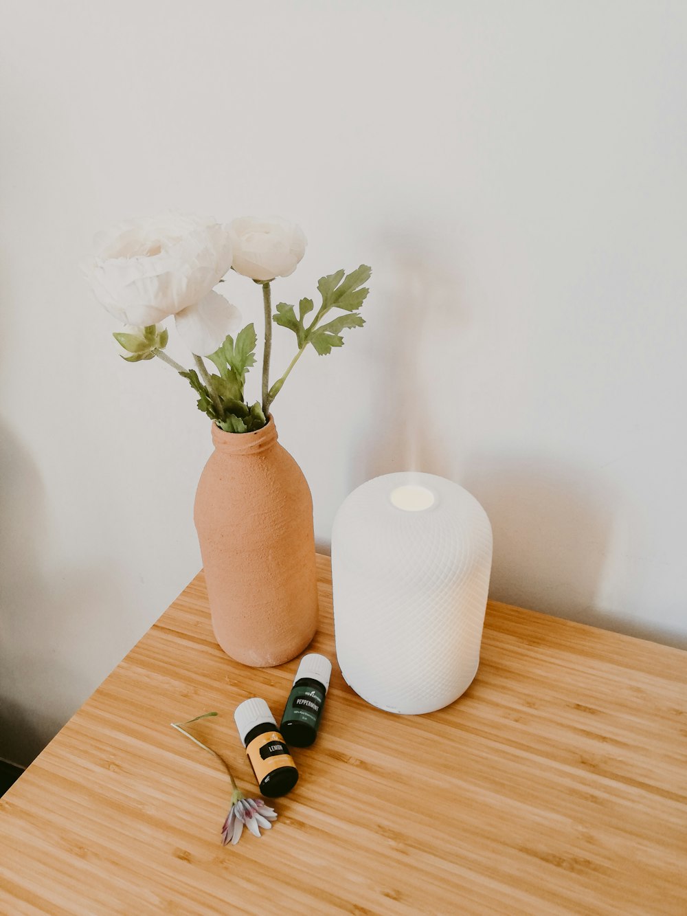 Jarrón de flores blancas y naranjas sobre mesa de madera marrón