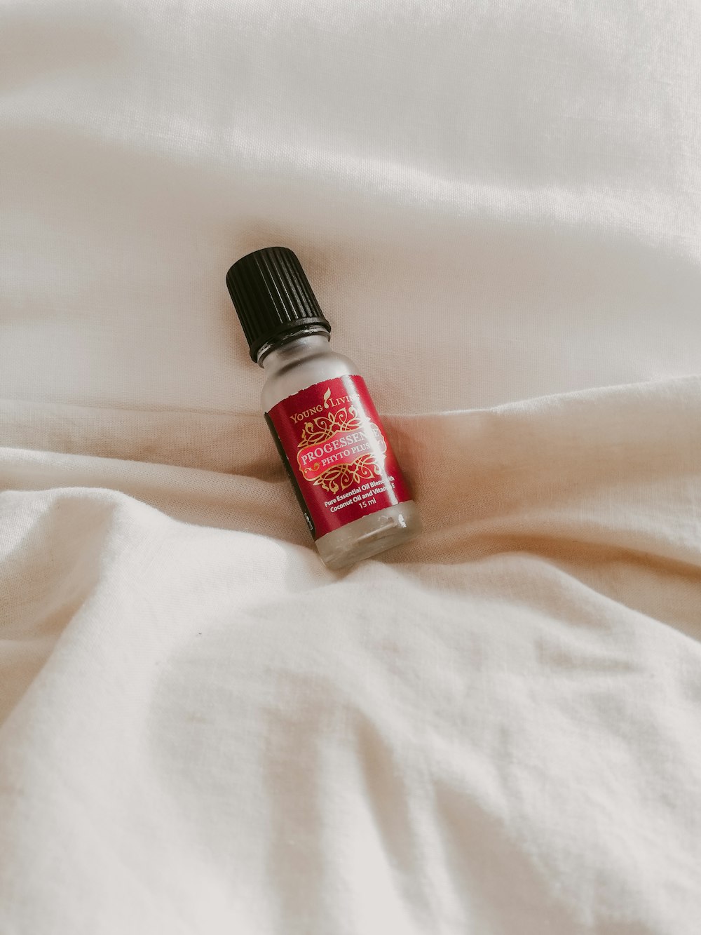 white and red plastic tube bottle on white textile