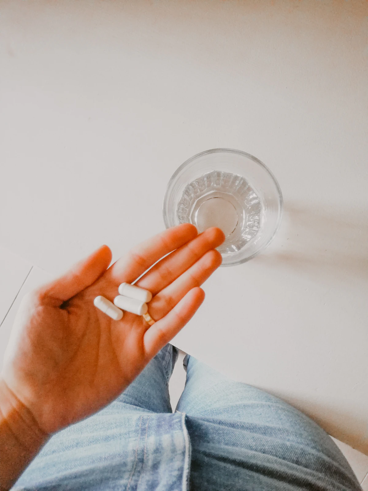 A person holding a white supplement capsule