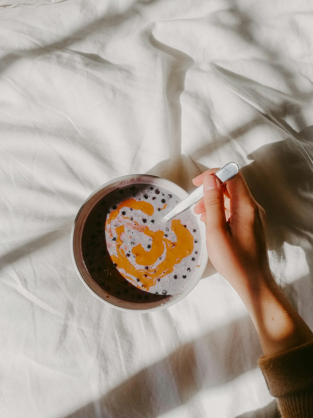 person holding brown and white ceramic bowl with brown liquid