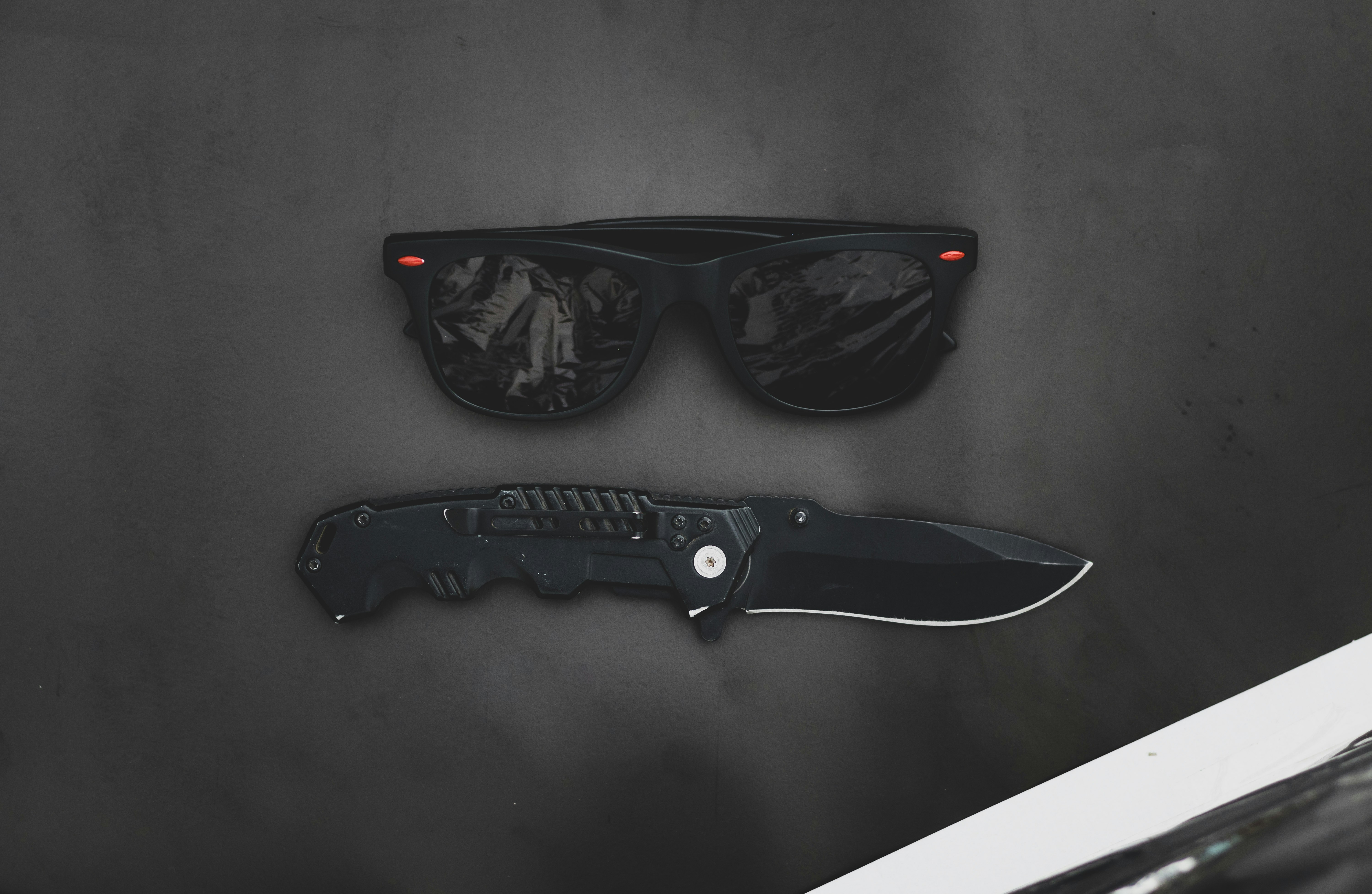 Sunglass and pocket army knife on a wooden background with a retro look.
