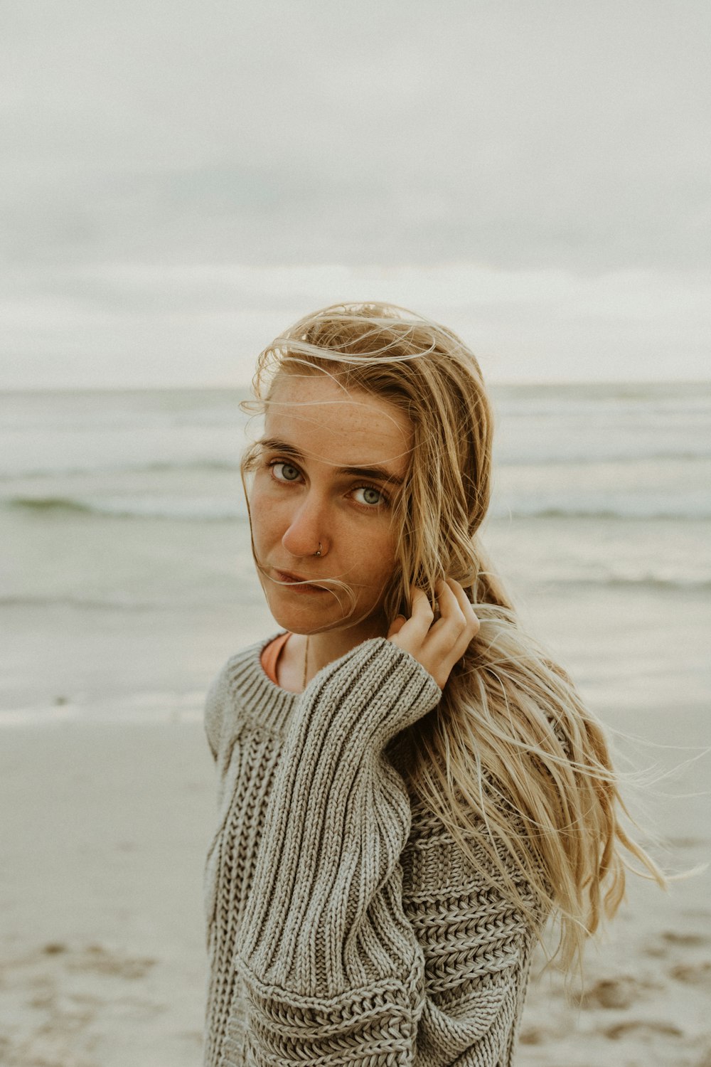 woman in white knit sweater on beach during daytime