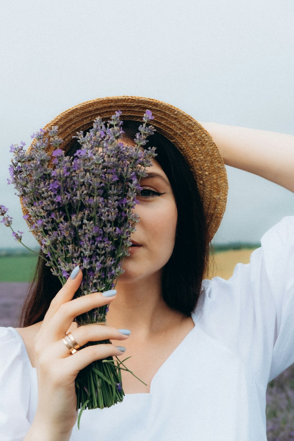 woman in white long sleeve shirt holding purple flowers