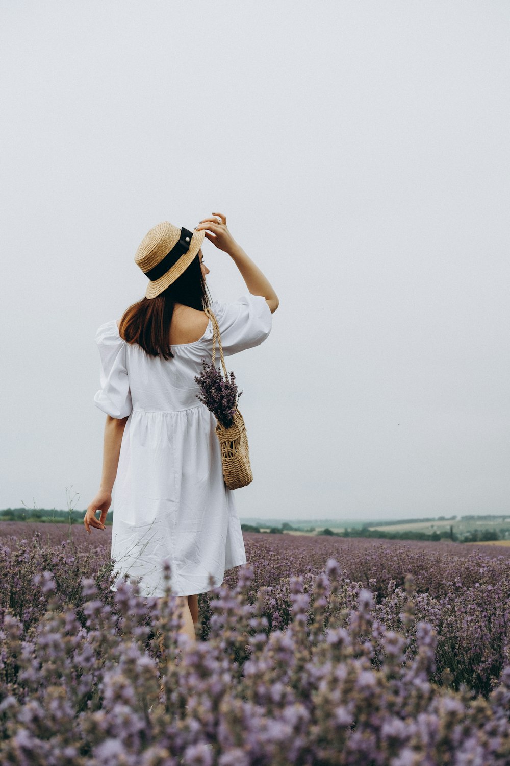 woman in white dress standing on purple flower field during daytime