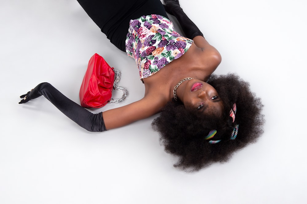 woman in black pink and green floral sleeveless dress lying on white floor