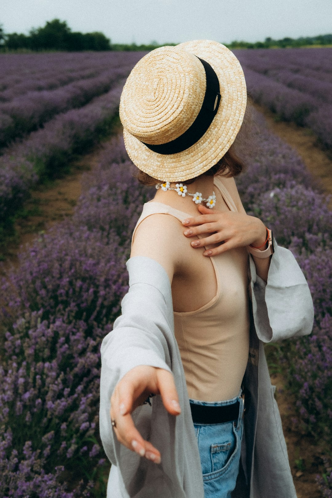 woman in white long sleeve shirt and brown straw hat standing on purple flower field during