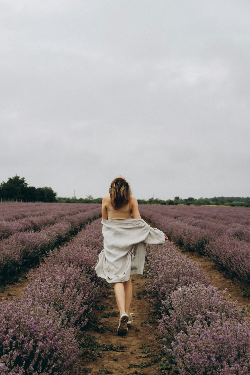 woman in white dress standing on purple flower field during daytime
