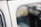 The image depicts a close-up view of a vintage car window, displaying its reflective glass surface. The interior and exterior details of the vehicle are blurred, creating a soft focus on the etched writing in the window that includes a logo and specifications.