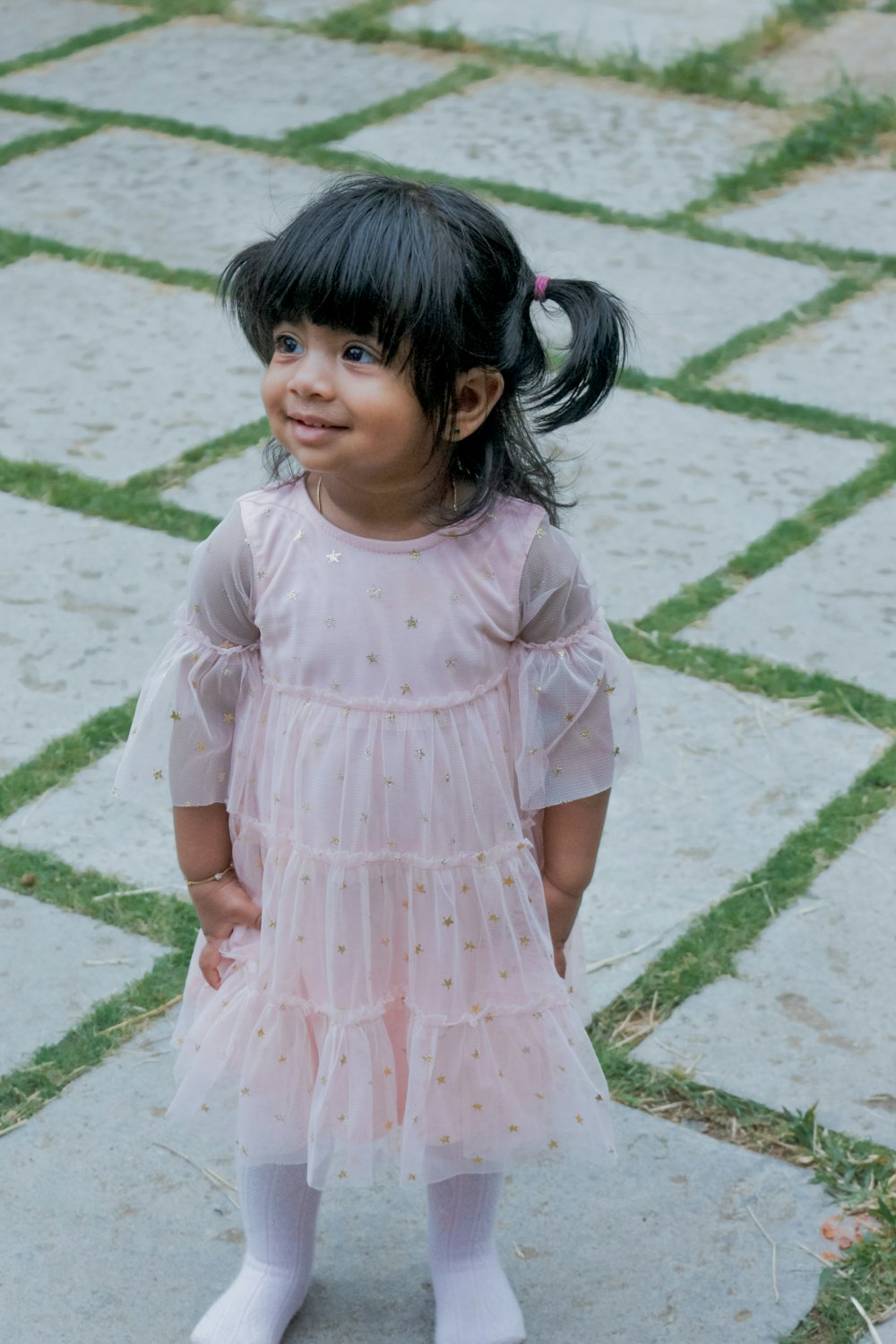 girl in pink dress standing on concrete floor during daytime