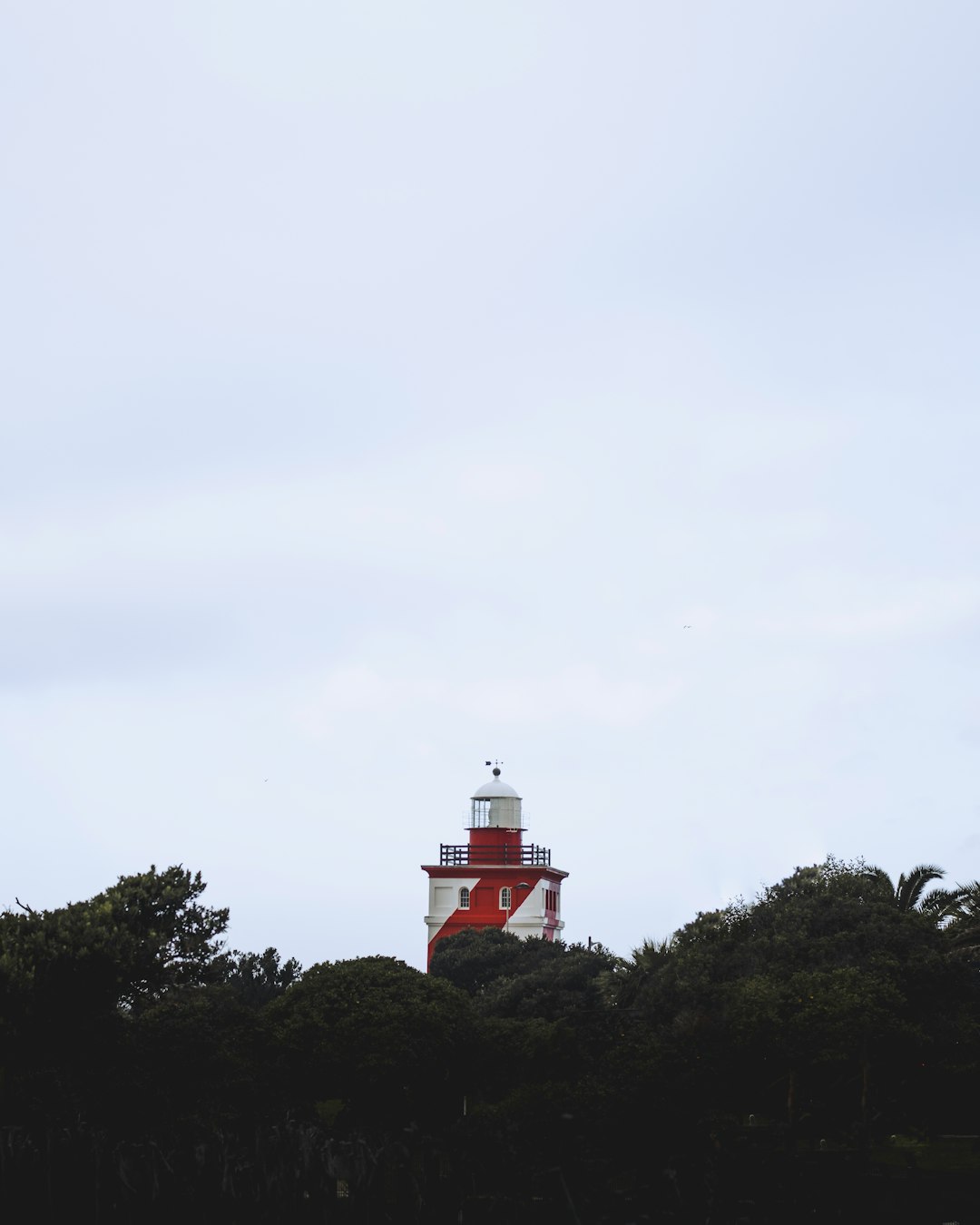 red and white lighthouse on top of hill