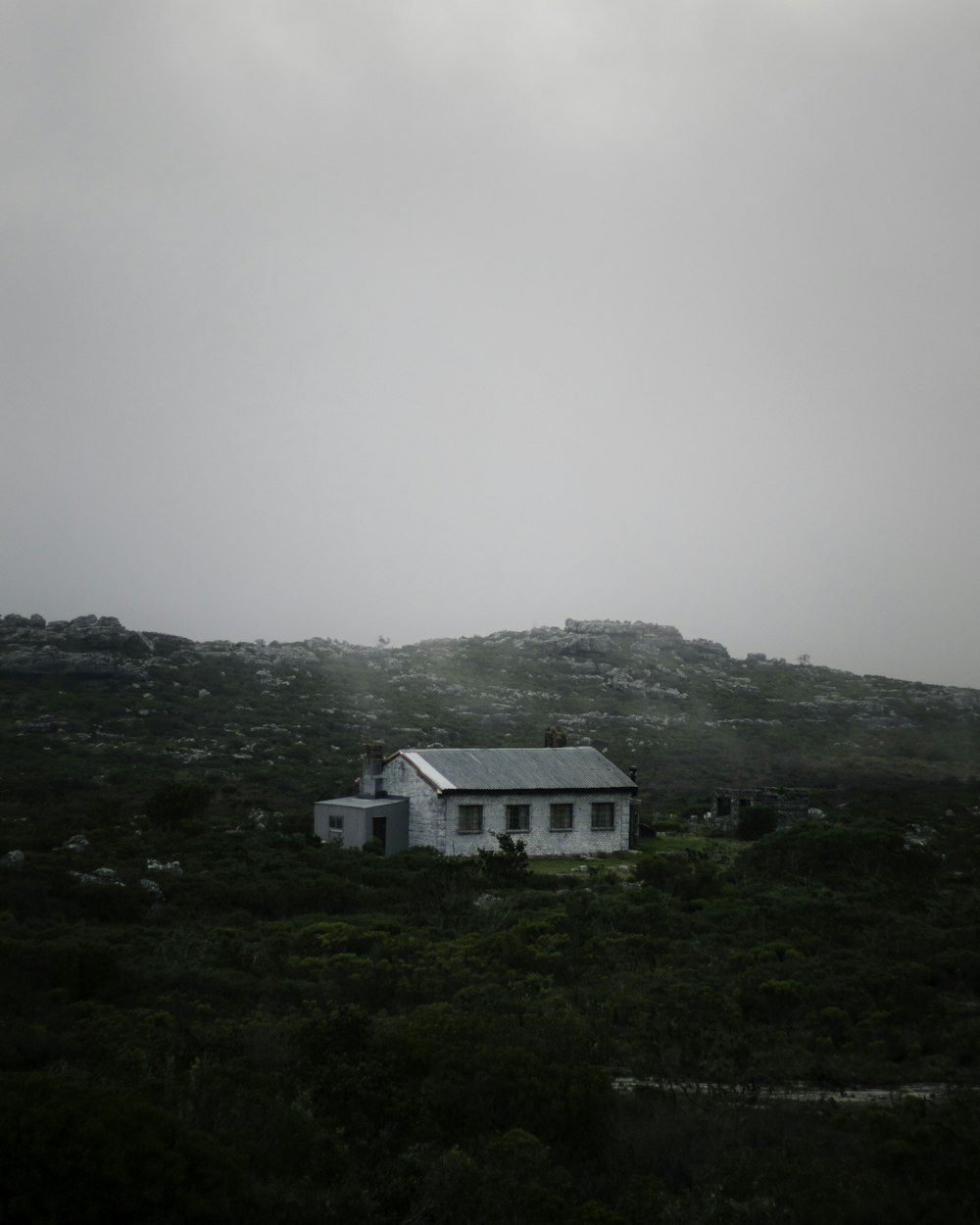 a white house sitting on top of a lush green hillside