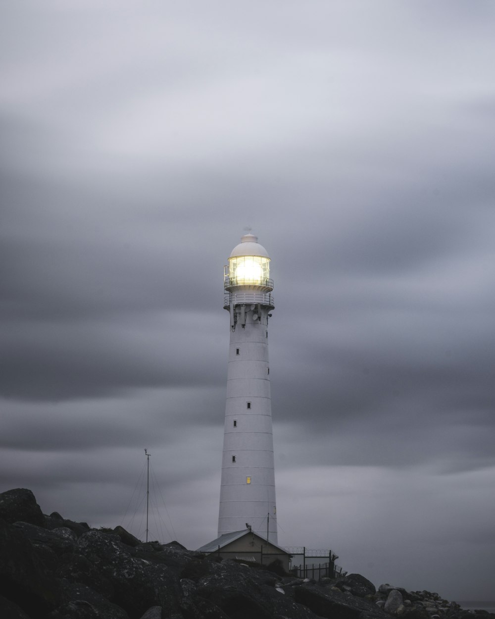 white and black lighthouse under gray clouds