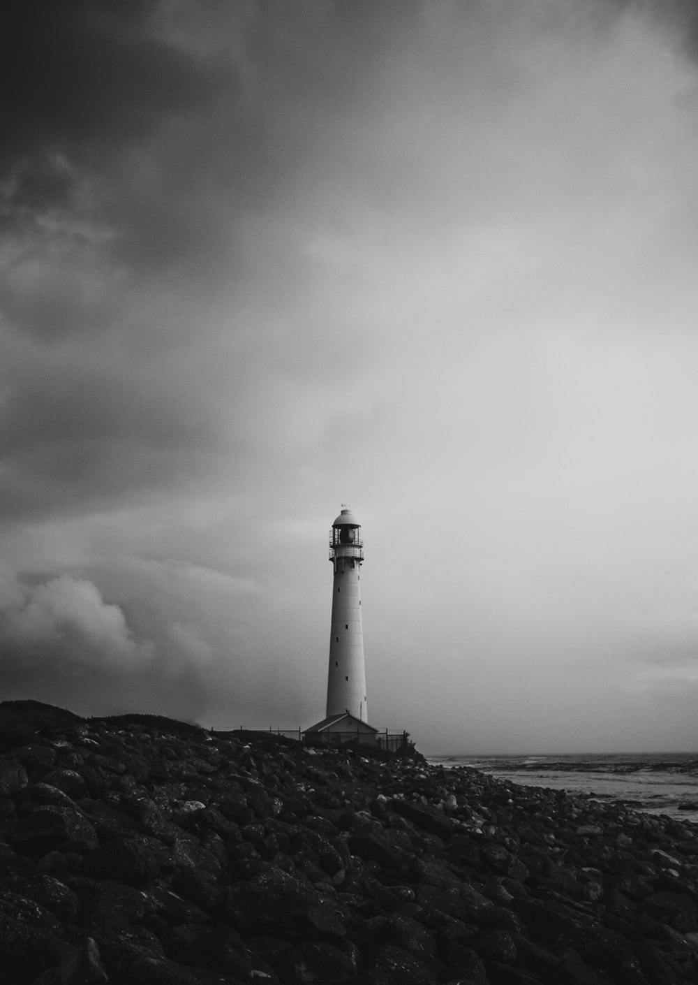 white and black lighthouse near body of water under cloudy sky
