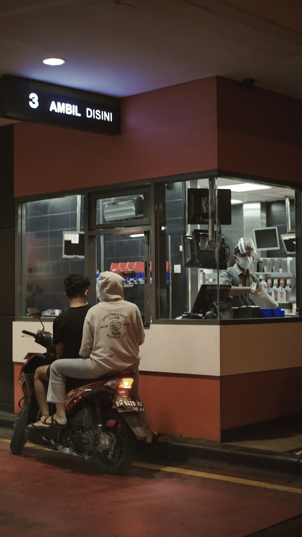 homme en chemise blanche assis sur une moto rouge et noire