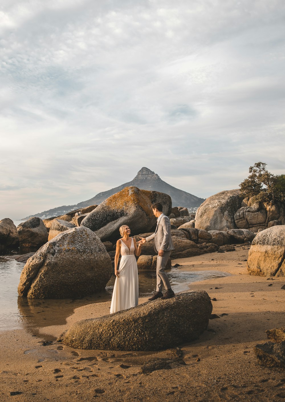 woman in white dress standing on brown rock near body of water during daytime