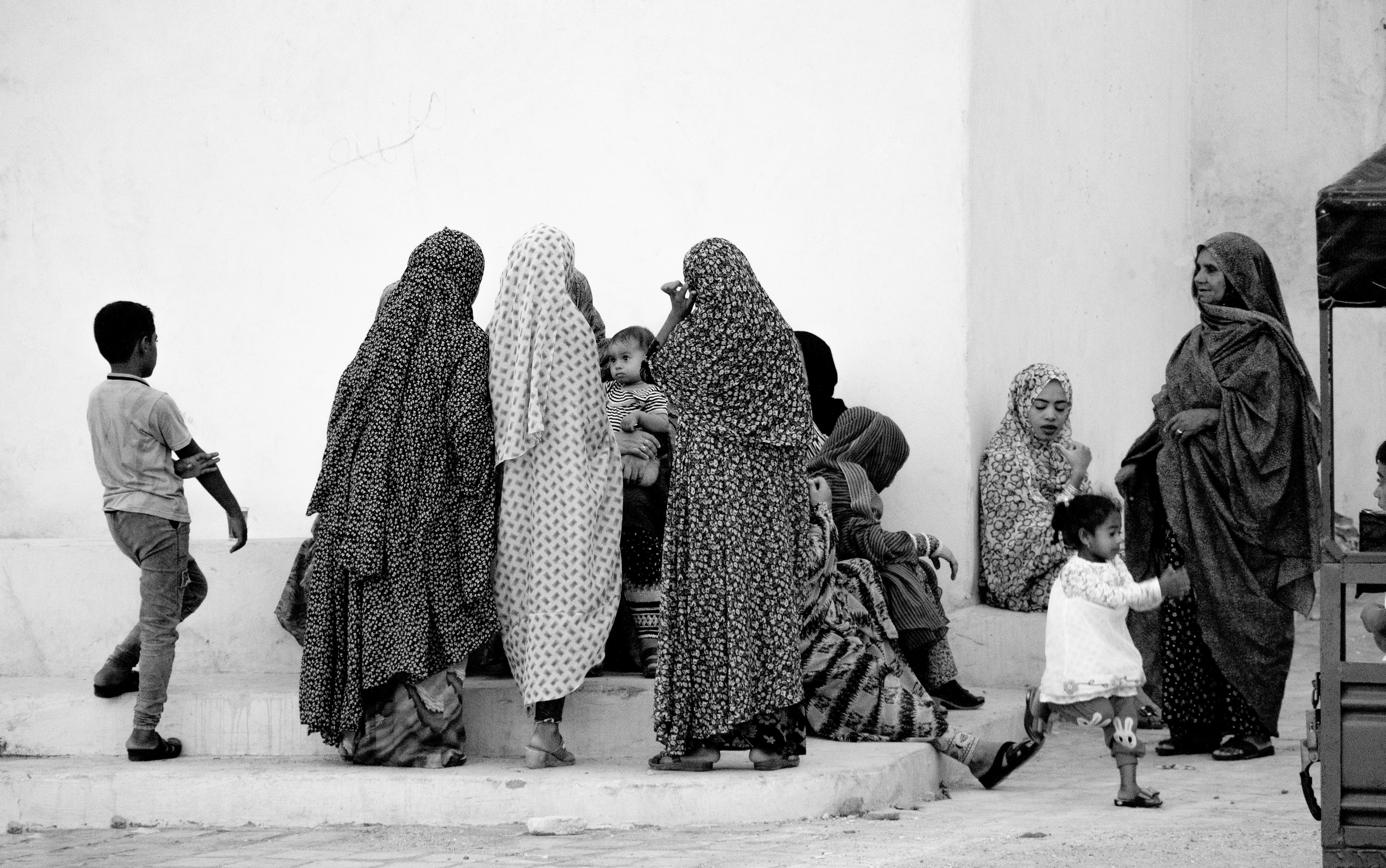 grayscale photo of people sitting on concrete stairs