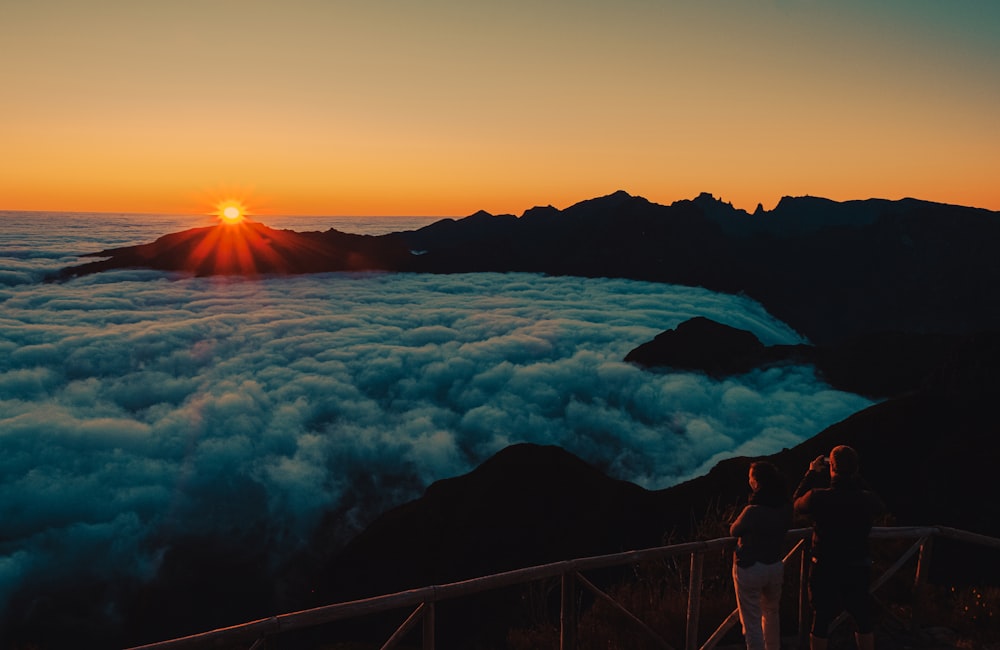 person standing on bridge over the sea during sunset