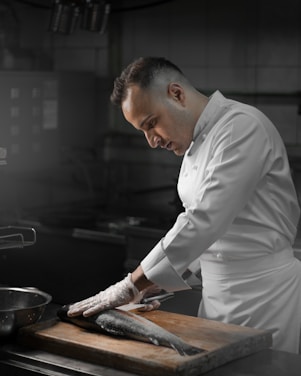 A chef preparing fish on a wooden cutting board.